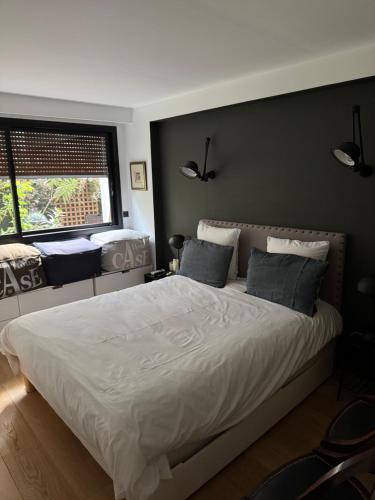 - une chambre avec un grand lit blanc et un mur noir dans l'établissement Appartement Design avec Jardin 4 pers 2 Chambres, à Paris