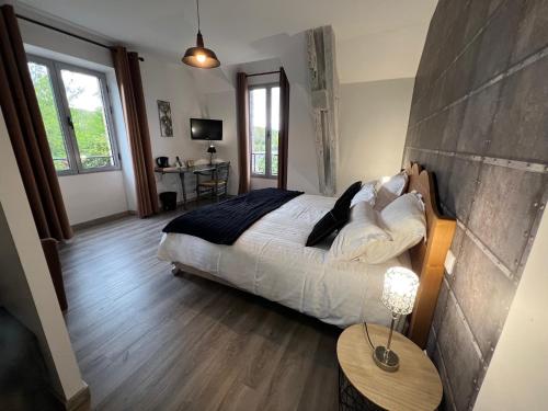 a bedroom with a bed and a table with a lamp at Logis Hôtel Auberge de Cartassac in Sarrazac