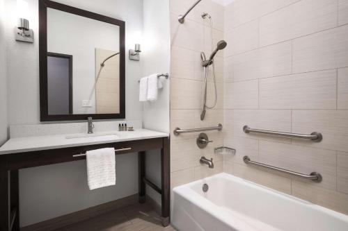 a bathroom with a tub and a sink and a mirror at Best Western Plus College Station Inn & Suites in College Station