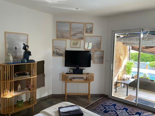 a living room with a tv and a table with a television at Chambre cosy Andernos Les Bains in Andernos-les-Bains