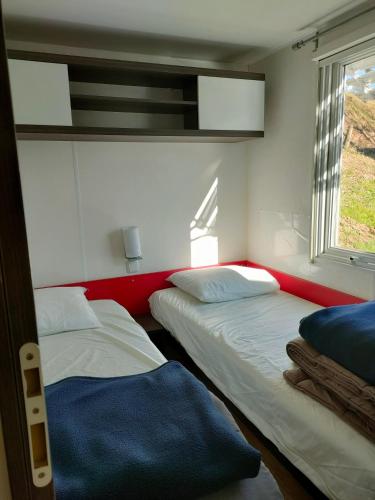two beds in a room with a window at Camping du Moulin de Thoard in Thoard