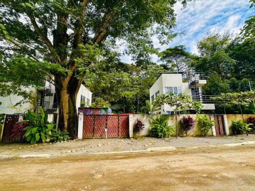 a fence with a tree in front of a house at Villa Carol in Punta Leona