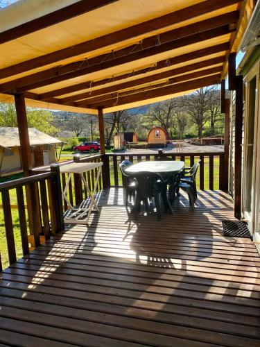 a patio with a table and chairs on a deck at Camping du Moulin de Thoard in Thoard