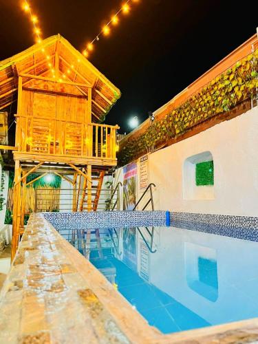 a swimming pool with a wooden house and a building at Hadiqah event venue in Mangangpico