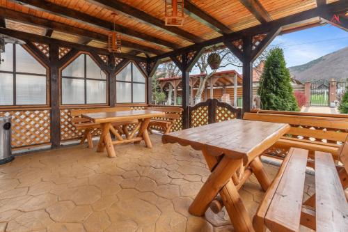 a pavilion with wooden picnic tables and benches at Luca Residence Beautiful Villa in Trăisteni