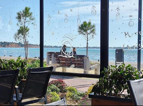 two people sitting on a bench looking out at the ocean at P & K Design LTD Flats in Nea Moudania