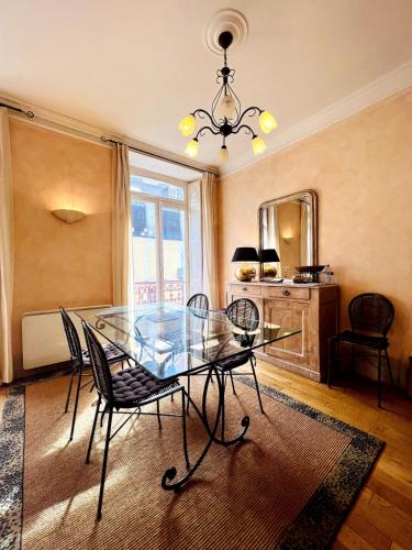 une salle à manger avec une table et des chaises en verre dans l'établissement Le Conti-chaleureux T3-hypercentre-wifi, à Cauterets