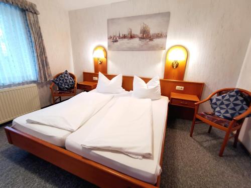 a bedroom with a large bed and two chairs at Landgasthof Leverenz "Traditionell & rustikal" in Neuenkirchen