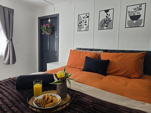 an orange bed with a tray of food on it at Cozy Flat London with private entrance in London