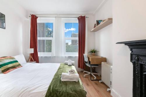 a bedroom with a bed and a desk and a window at Stay on Brick Lane in London