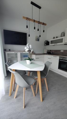 a white kitchen with a table and chairs and a tv at Pusteblume in Graal-Müritz