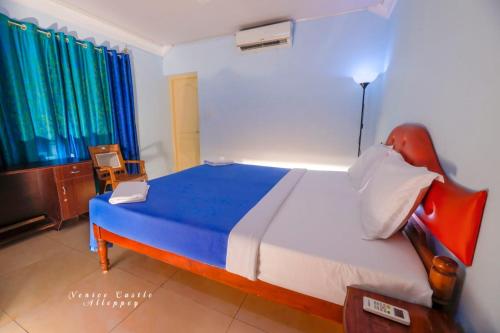 a bedroom with a large bed with blue and white sheets at Venice Castle in Alleppey