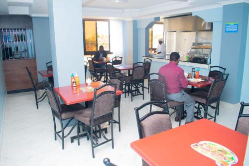 two people sitting at tables in a restaurant at Laquita hotel in Nakuru