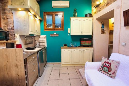 a kitchen with green walls and white cabinets at Venetis Luxury Apartments in Chios