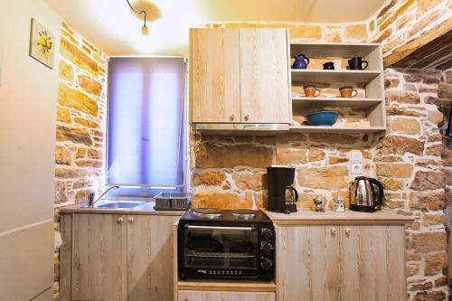 a kitchen with a stove and a stone wall at Venetis Luxury Apartments in Chios