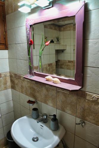 a bathroom with a sink and a mirror and flowers at Venetis Luxury Apartments in Chios