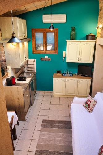 a kitchen with green walls and white cabinets at Venetis Luxury Apartments in Chios