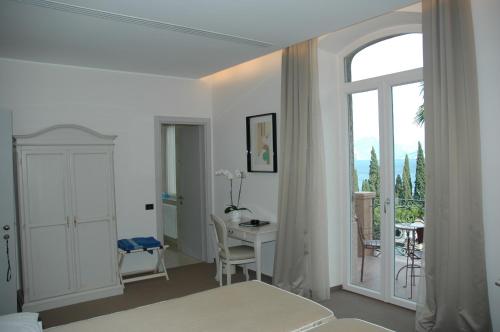a bedroom with a bed and a desk and a window at Bellevue San Lorenzo (Adults Only) in Malcesine