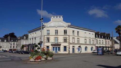 un grand bâtiment blanc avec des plantes devant lui dans l'établissement Appartement Pontivy, à Pontivy
