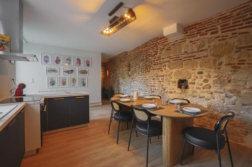 une salle à manger avec une table et un mur de briques dans l'établissement L'Héritage Agenais Coeur du centre ville, à Agen