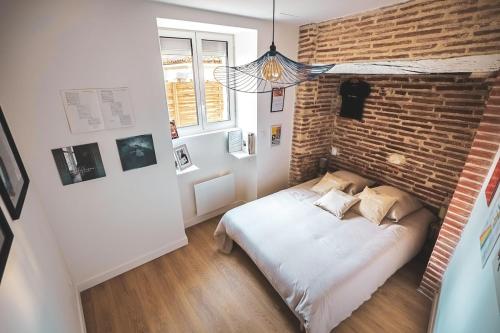 une chambre avec un mur de briques et un lit dans l'établissement L'Héritage Agenais Coeur du centre ville, à Agen