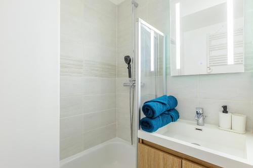 La salle de bains est pourvue d'un lavabo et d'une douche avec des serviettes bleues. dans l'établissement Le Duplex - City Center - DISNEY 10 min - PARIS 28 min - GARE 4 min - PARKING - Free WIFI, à Bussy-Saint-Georges
