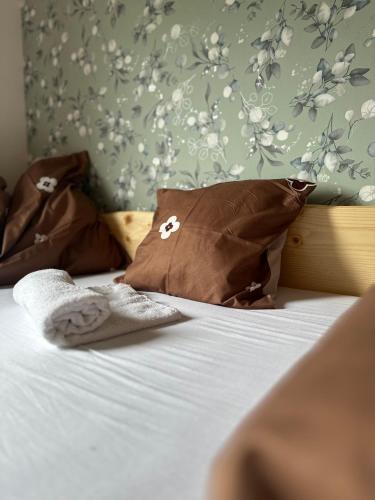 a bed with two brown pillows and a floral wall at Edenski vrt in Ivančna Gorica