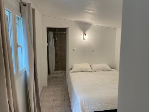 a white bedroom with a bed and a window at 2 mini villas indépendantes campagne saint flo in Saint-Florent