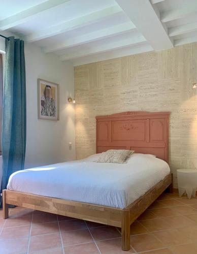 une chambre avec un grand lit avec une tête de lit en bois dans l'établissement L'Orée rouge de la Forêt, à Villefranche-Sur-Cher
