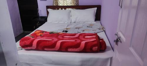 a bed with a red blanket on top of it at Royal villa Homestay in Munnar