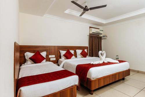a bedroom with two beds with red and white sheets at Hotel Lakshmi Grand in Chennai