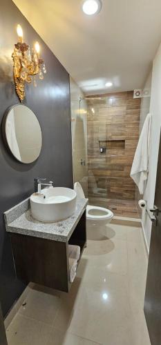 a bathroom with a sink and a toilet and a mirror at Torre 5 Mazatlán Versace Style in Mazatlán