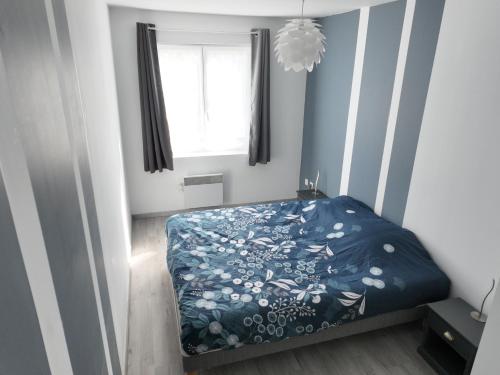 a bedroom with a bed with a blue comforter and a window at Grand appartement de ville avec 2 places de parking privées intérieur in Beuvrages
