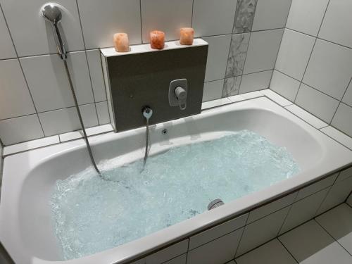 a bath tub filled with blue water in a bathroom at Entspannung pur! Privater Kinosaal & Whirlpool in Essen