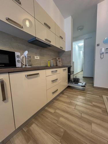 a kitchen with white cabinets and a wooden floor at Flabelline in Bar