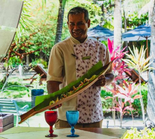 a man holding a tray of food on a table at CASA ACAYU in São Miguel dos Milagres