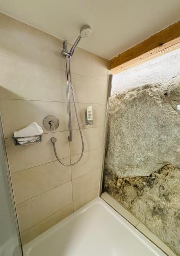a shower in a bathroom with a stone wall at APT. STONE-LODGE in Salzburg