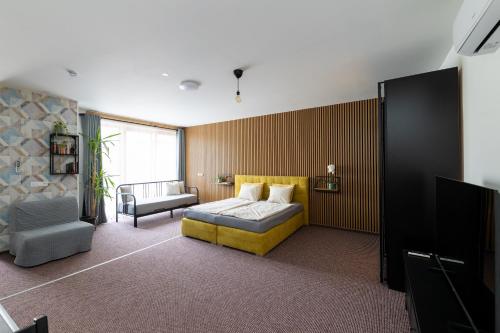 a bedroom with a bed and a couch and a chair at VOUSATÁ DÁMA - PS3 - Parking free in Prague
