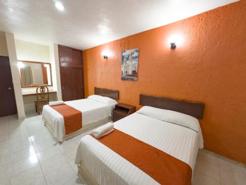 a hotel room with two beds and an orange wall at Hotel Uxulkah in Campeche