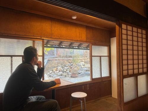a man looking out of a window in a room at Osugi-ya 大杉屋 in Wazuka