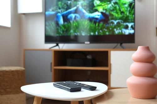 a living room with a tv and a remote control on a table at Charmant appartement Lille Centre St Michel in Lille