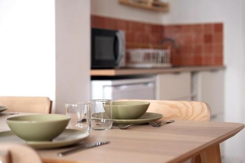 a wooden table with two bowls and glasses on it at Charmant appartement Lille Centre St Michel in Lille