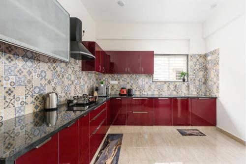 a kitchen with red cabinets and tiles on the wall at OBS Serviced Apartments HSR Layout Bangalore in Bengaluru