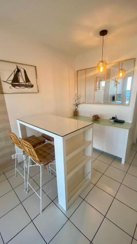 une cuisine avec un comptoir blanc, une table et des chaises dans l'établissement Le rêve d'azur, à Saint-Raphaël