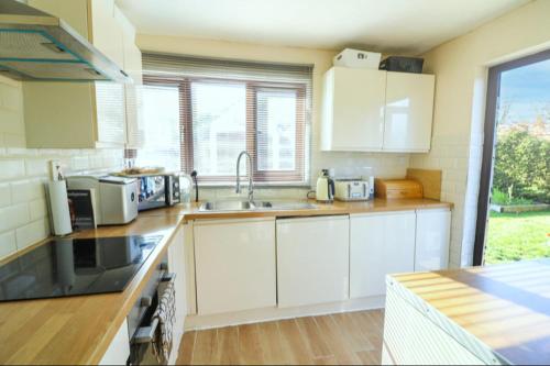 a kitchen with white cabinets and a sink at Pet Friendly Home in Chelmsford-Hot Tub-Sleeps 6 in Latchingdon and Snoreham