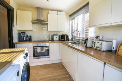 a kitchen with white cabinets and a sink at Pet Friendly Home in Chelmsford-Hot Tub-Sleeps 6 in Latchingdon and Snoreham