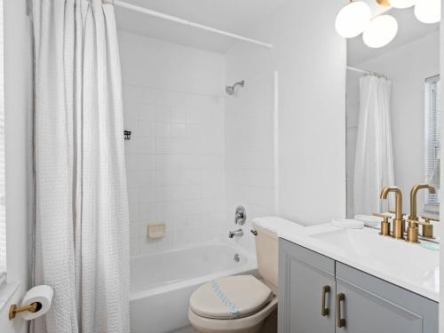 a white bathroom with a tub and a toilet and a sink at SUPER BOHO- At LAKE TOHO's WATER SLEEPs 6 in Kissimmee