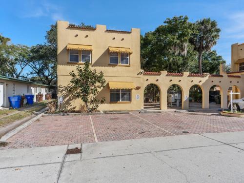 a large yellow building with a red brick driveway at SUPER BOHO- At LAKE TOHO's WATER SLEEPs 6 in Kissimmee