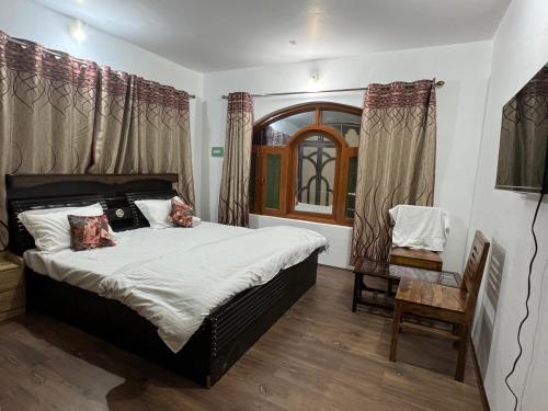 a bedroom with a large bed and a chair at Peak View Guest House Gurez in Wāmpor