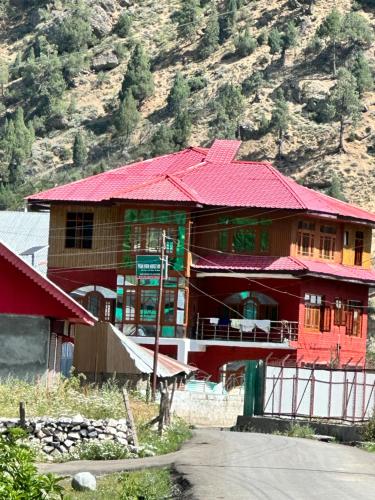 a large building with a red roof on a mountain at Peak View Guest House Gurez in Wāmpor